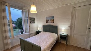 Um quarto com uma cama, duas mesinhas de cabeceira, uma janela com vista e uma porta.