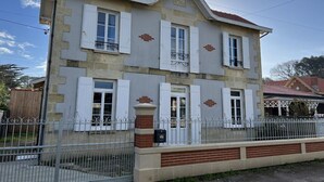 Um edifício de dois andares com fachada simétrica, persianas brancas e telhado telhado.