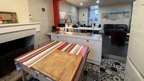 Uma cozinha compacta com área de jantar, lareira e sala de estar com sofá de couro preto.
