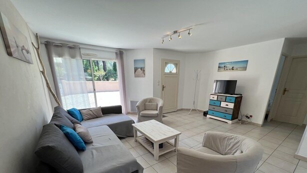 Ein Wohnzimmer mit einer Couch, einem Sessel, einem Couchtisch und einem Fernsehmöbel.