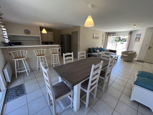 A spacious kitchen with a dining area, bar stools, and a sofa.