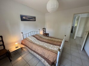 A bedroom with a bed, a nightstand, a chair, a lamp, and a painting on the wall.