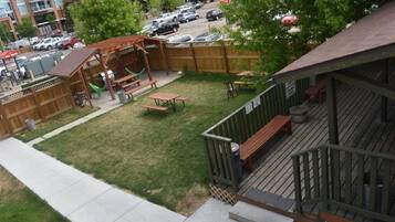 Un patio trasero con una terraza de madera, mesas de picnic y una hamaca.