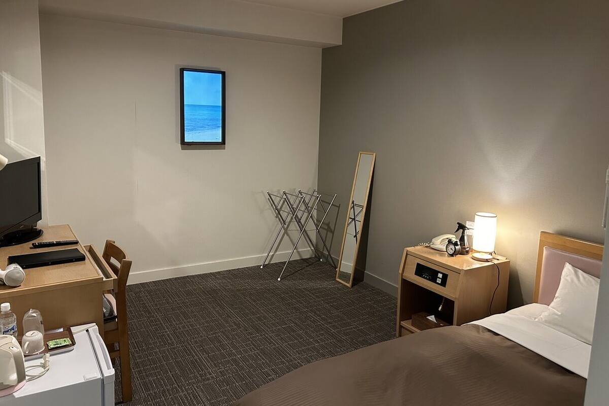 Une chambre d’hôtel équipée d’un bureau, d’une chaise, d’un lit, d’une table de chevet, d’une lampe et offrant une vue sur la mer.