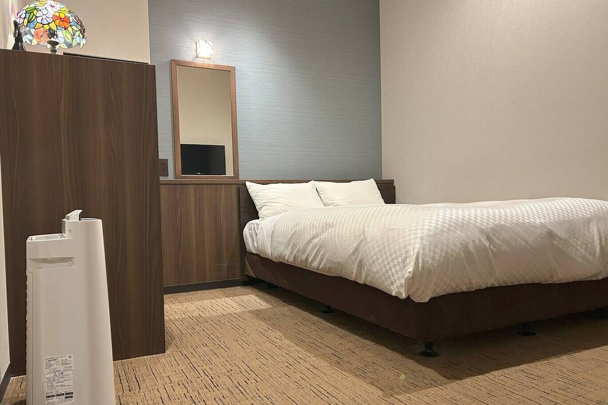 Une chambre à coucher avec un lit, une armoire en bois, un miroir et une lampe.