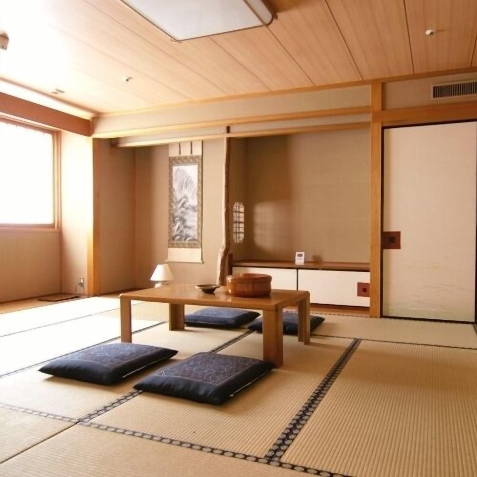 A tatami mat room with a low table, cushions, and a sliding door.