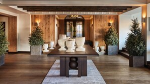 A dining area with a wooden table, potted plants, and a view through an archway. - Madeline Hotel And Residences, Auberge Resorts (Telluride)