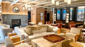 A cozy lounge area with a fireplace, comfortable seating, and a view of snowy mountains. - Madeline Hotel And Residences, Auberge Resorts (Telluride)