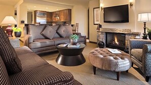 A living room with a sofa, ottoman, coffee table, fireplace, and a flat-screen TV.
