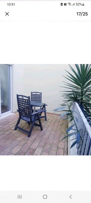 Enjoy a peaceful moment on the balcony with a potted plant and comfortable seating for two.