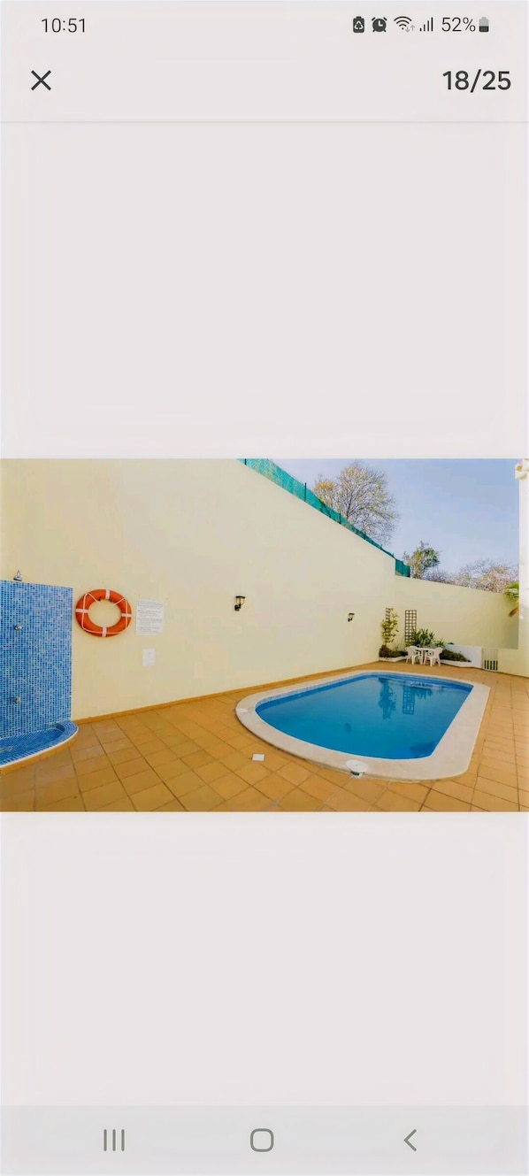 Enjoy a refreshing swim in the pool surrounded by a low wall and a fence.