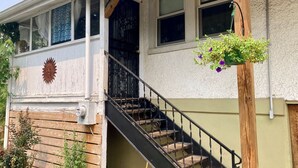 A two-story house with a wooden staircase and a flower basket hanging on the exterior wall. - Sunny Blue Bungalow near Nashville in Historic Downtown Murfreesboro (Murfreesboro)