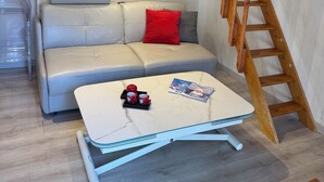 Un salon moderne avec un canapé, une table basse et une échelle en bois appuyée contre le mur.