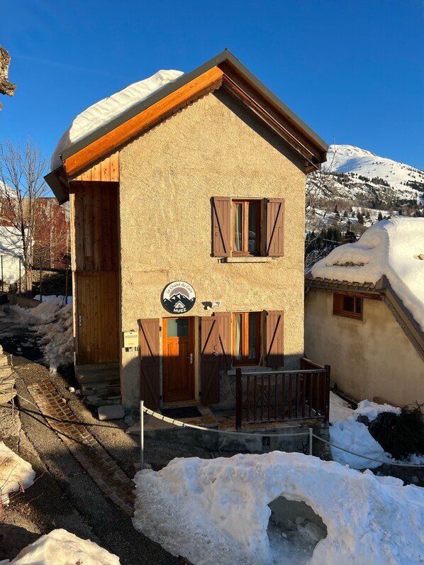 A chalet-style building with wooden shutters, a balcony, and a sign indicating it is a ski resort.