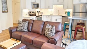 A modern kitchen with white cabinets, stainless steel appliances, and a bar area.