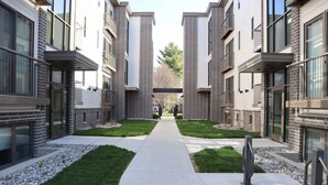 A modern apartment building with a central walkway, brick facade, and glass windows.