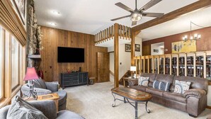 A living room with a brown leather sofa, a wooden coffee table, and a television mounted on the wall. - Deer Mountain Retreat near RMNP! #3206 (Estes Park)