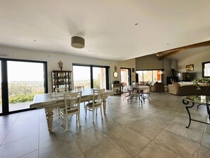 A spacious living area with a dining table and chairs, a sofa, and a television.