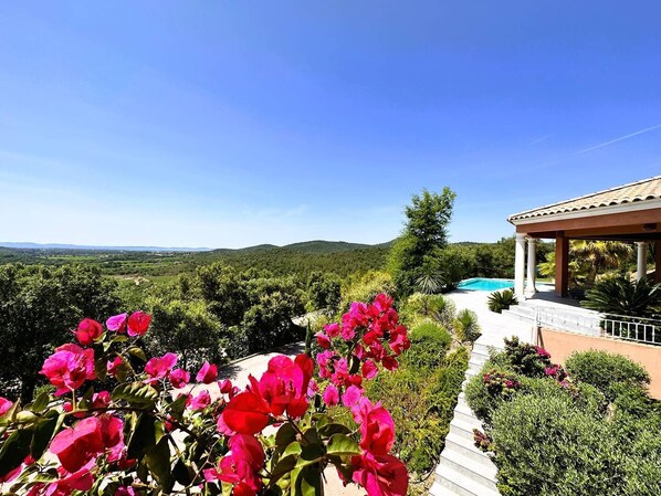 A villa with a pool, surrounded by lush greenery and hills.