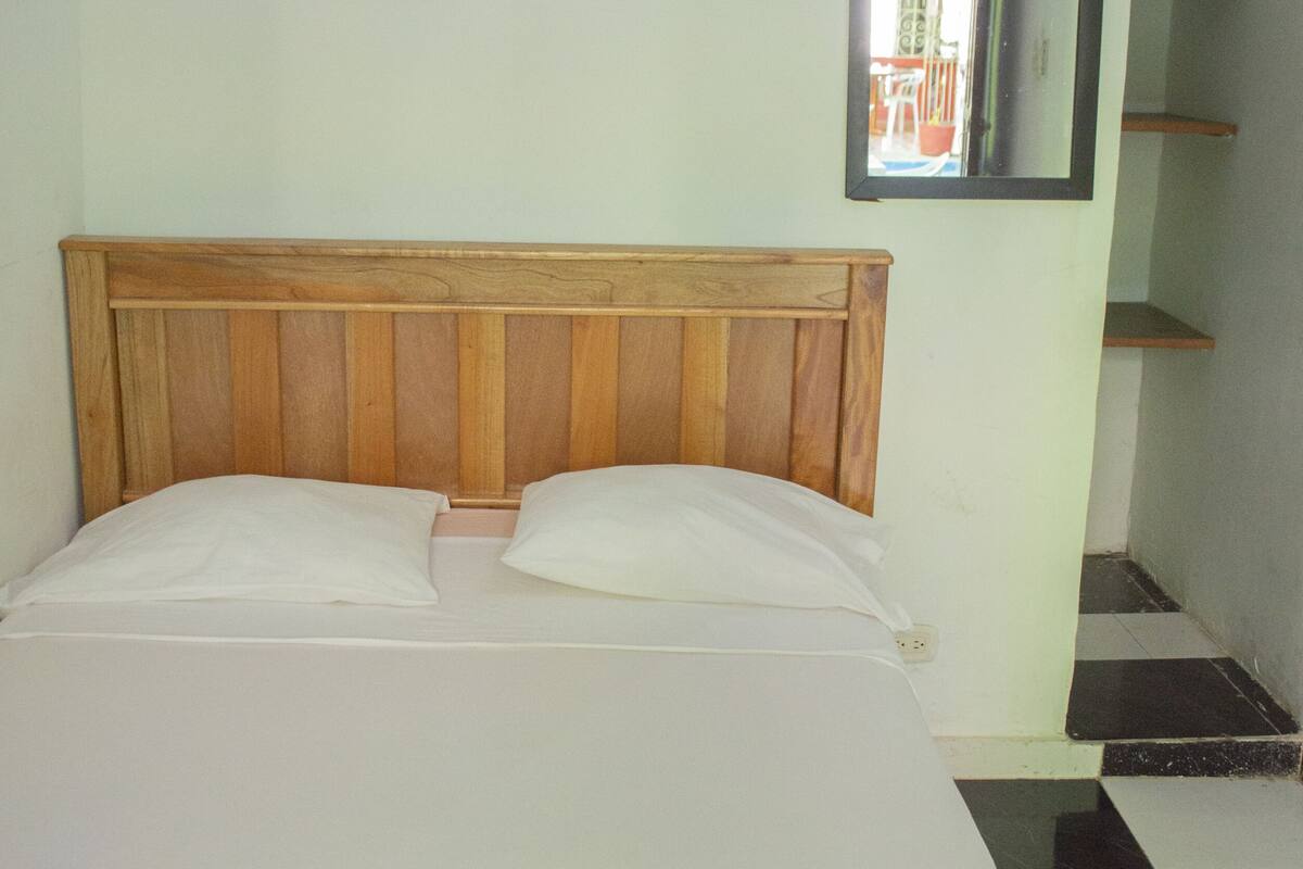 A bed with a wooden headboard, white bedding, and a checkered floor.