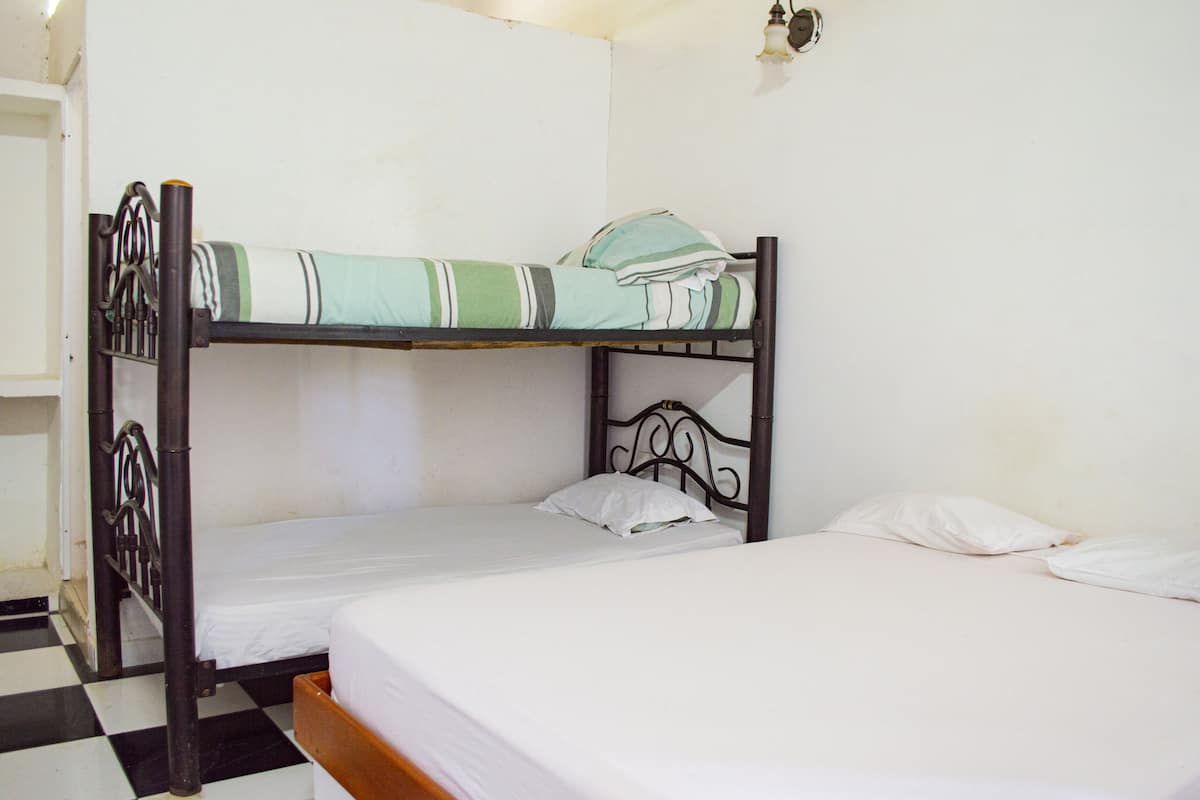 A bunk bed with a green and white striped blanket and a white pillow.