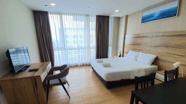 Habitación de hotel con cama, escritorio, silla y televisor.