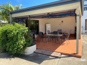 An outdoor patio with a covered seating area, a grill, and a refrigerator. - Hervey Bay Motel (Urangan)