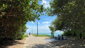 A paved pathway leading to a beach with benches and a picnic table. - Hervey Bay Motel (Urangan)