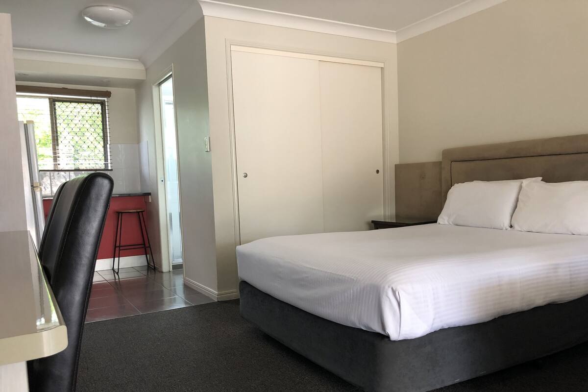 Um quarto com uma cama, uma escrivaninha, uma cadeira e uma porta.