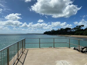 A concrete walkway with metal railings overlooking a calm sea and a distant shoreline with trees. - Hervey Bay Motel (Urangan)