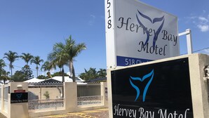 A sign for the Hervey Bay Motel with a logo, address, and a gate with a 'VACANCY' sign. - Hervey Bay Motel (Urangan)