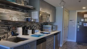 Una cocina moderna con electrodomésticos de acero inoxidable, lavavajillas y salpicadero de azulejos.