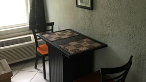 Un coin repas avec une table et des chaises, une œuvre d’art encadrée au mur et une fenêtre avec des rideaux.