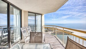 Un balcon avec vue sur l’océan, aménagé avec des chaises et une table.