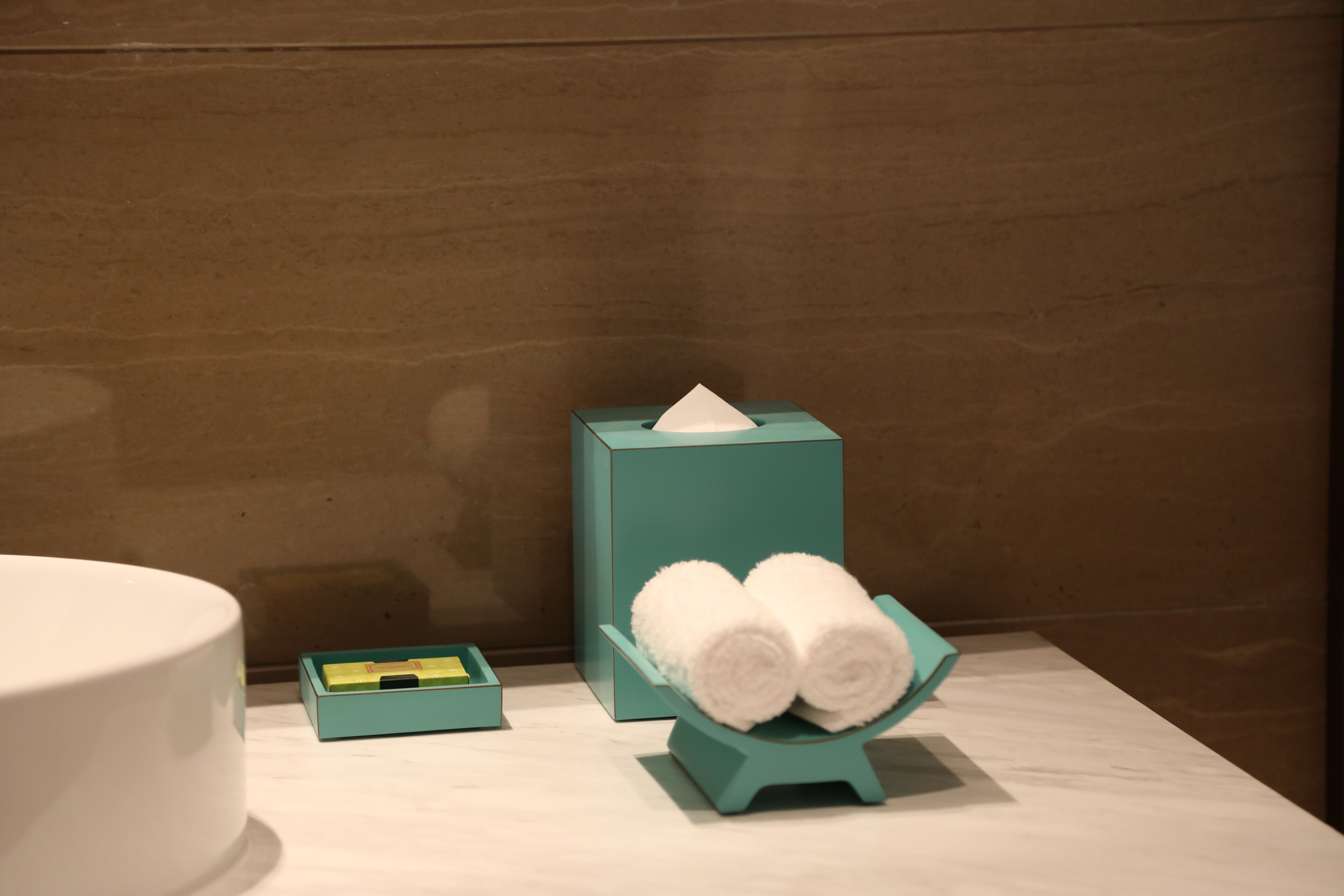 A bathroom with a white sink, a teal towel warmer, and a green tissue box.