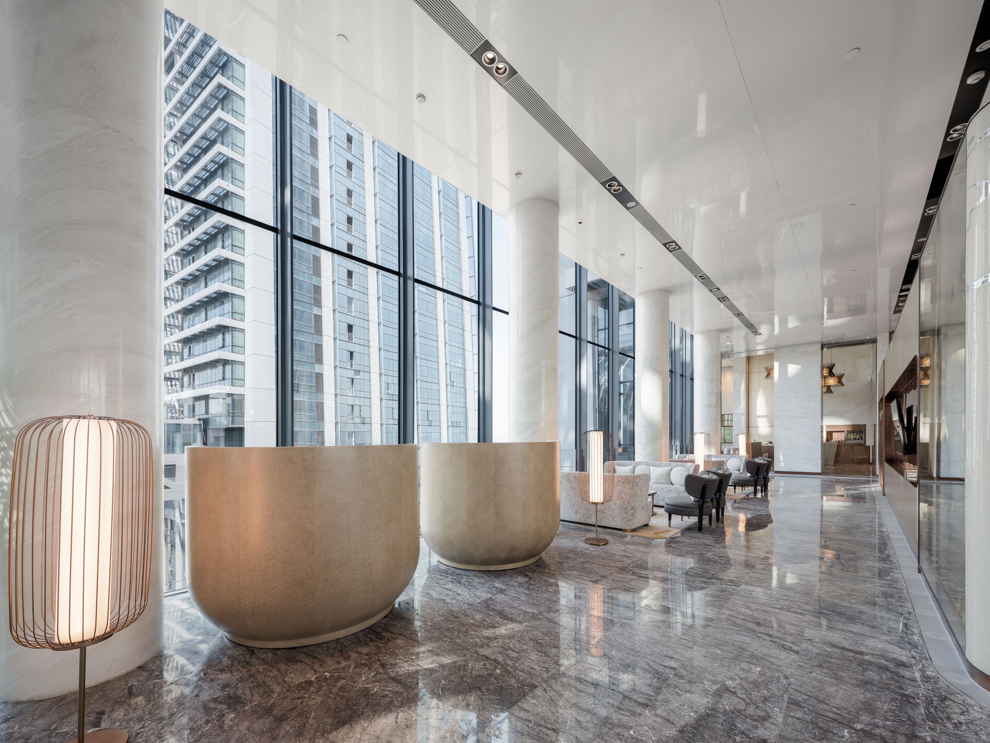 A spacious lobby with large windows, marble flooring, and modern furnishings.