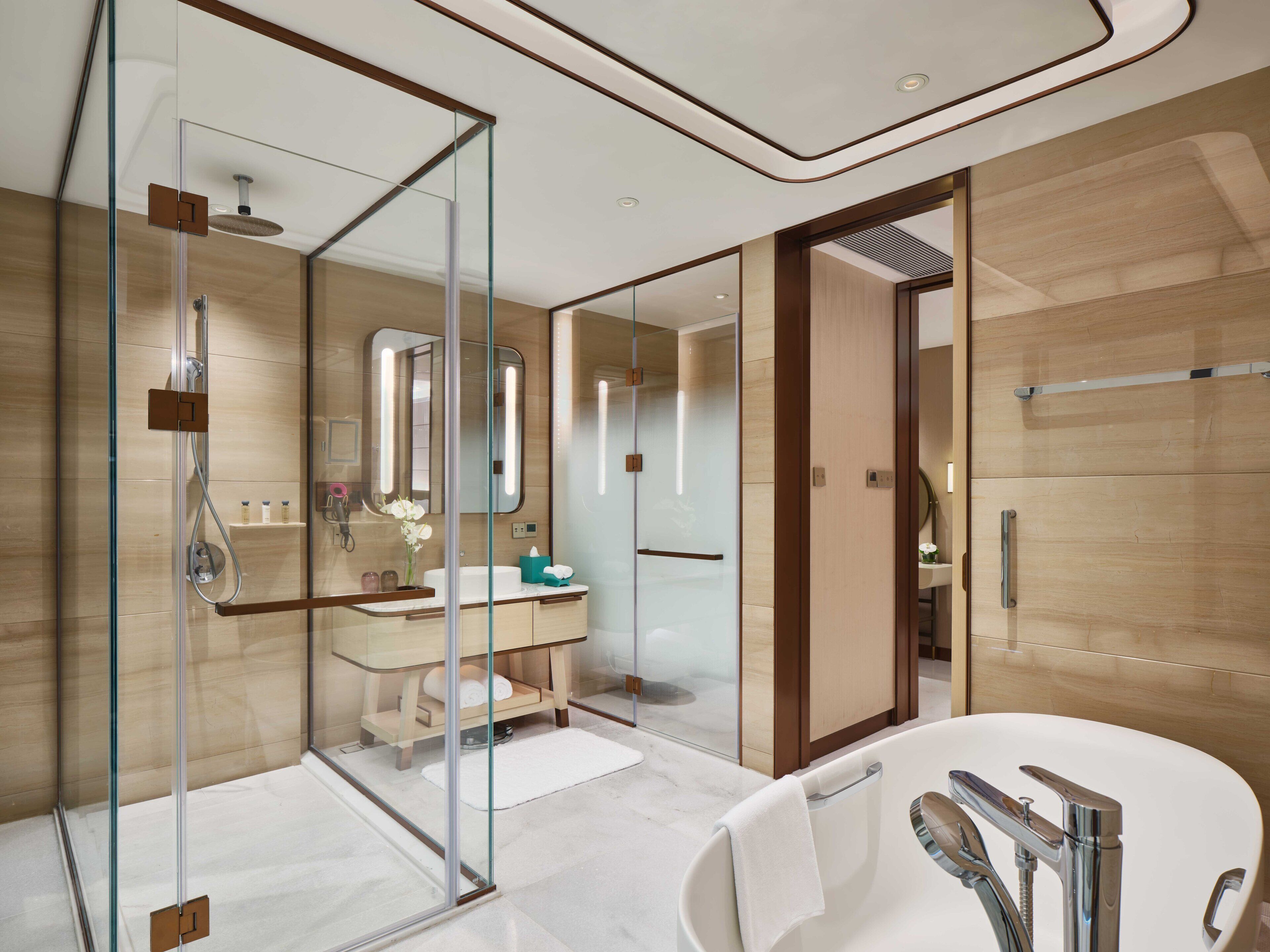 A modern bathroom with a glass-enclosed shower, a white sink with a mirror, and a large bathtub.
