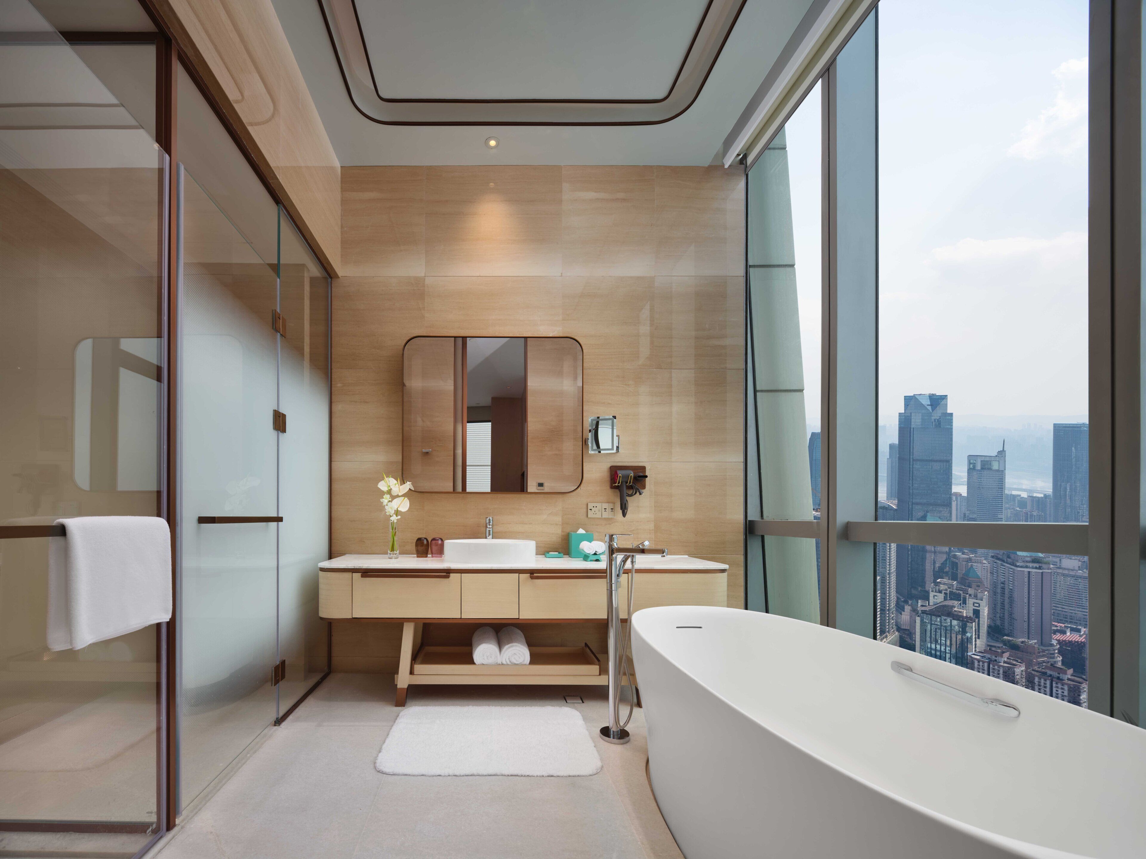A modern bathroom with a large bathtub, dual sinks, and a large mirror.