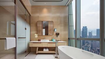 A modern bathroom with a large bathtub, dual sinks, and a large mirror.