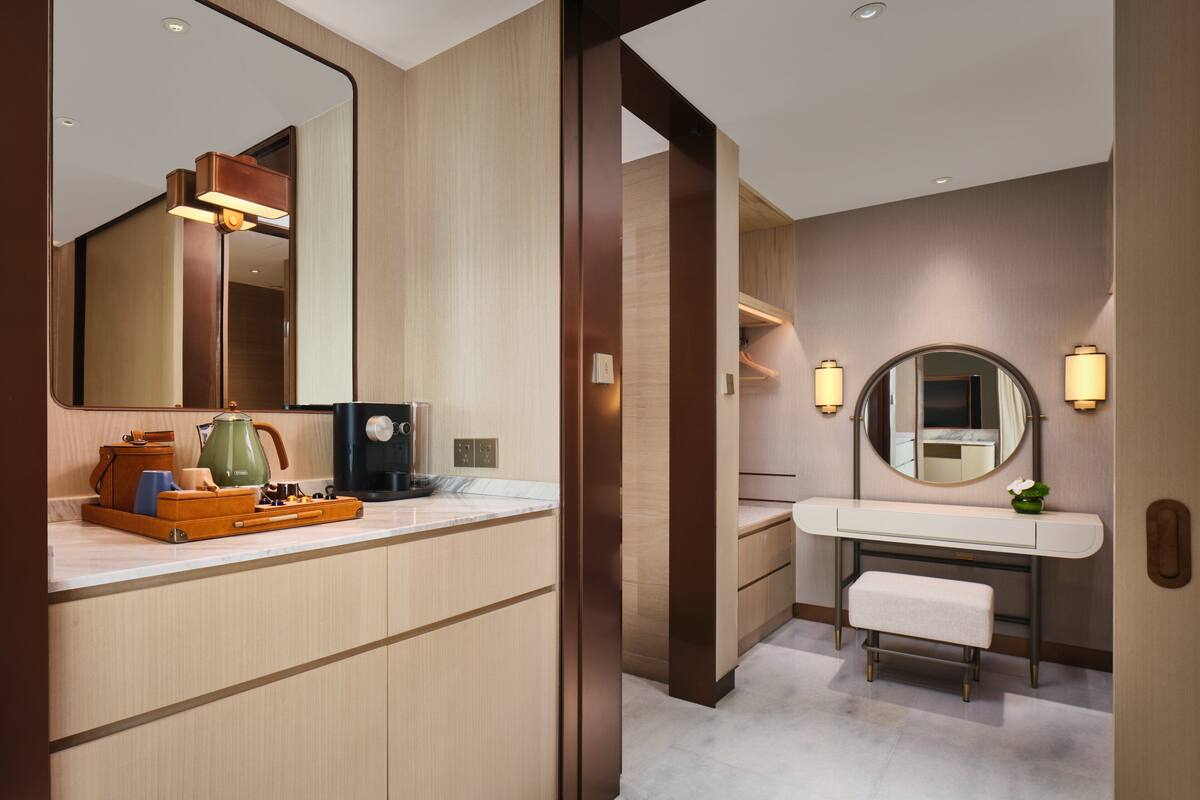 A modern bathroom with a large mirror, a sink, and a bench.