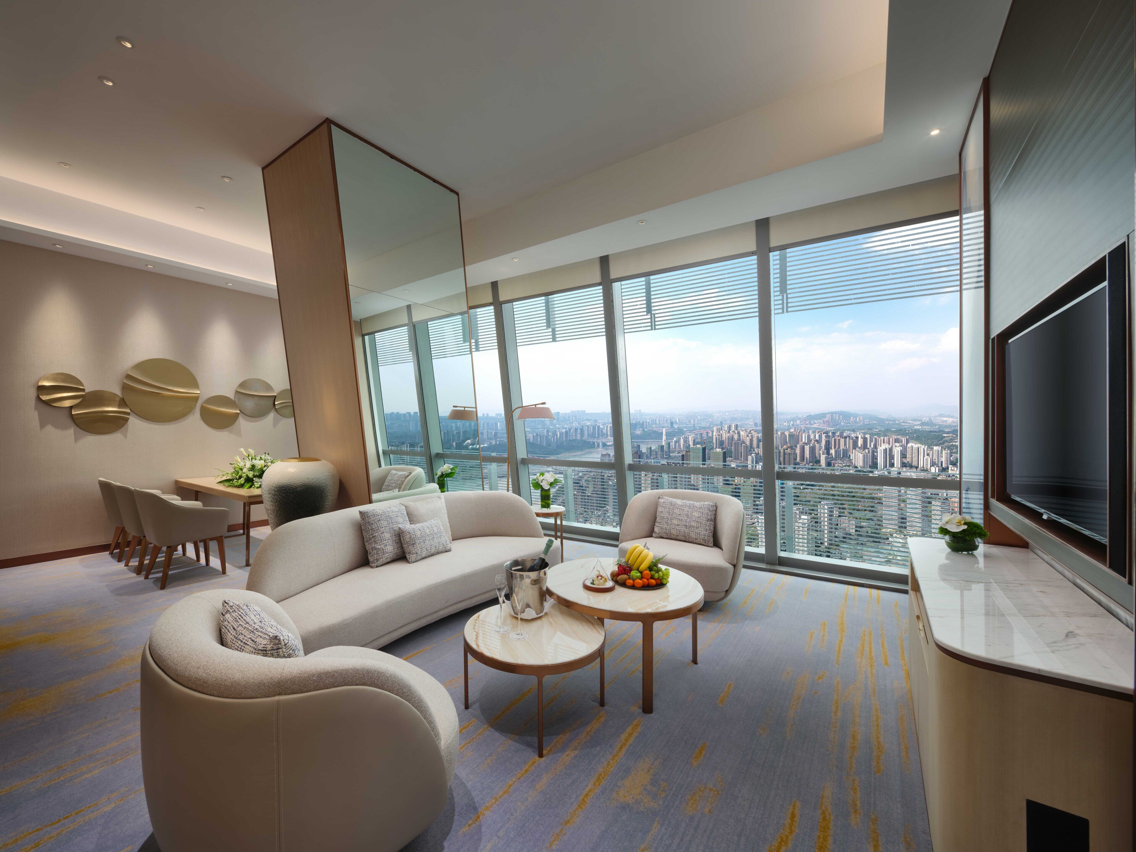 A modern living room with a sofa, armchairs, a coffee table, and a dining area with a table and chairs.