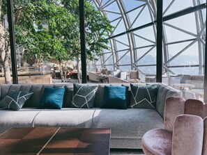 A modern lounge area with a sofa and chairs, large windows, and a view of the outdoors. - InterContinental Chongqing Raffles City by IHG (Chongqing)