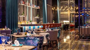 Un área de bar moderna con asientos, una barra y una lámpara decorativa.