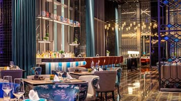A modern bar area with seating, a bar counter, and a decorative light fixture.
