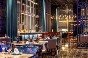 A modern bar area with seating, a bar counter, and a decorative light fixture. - InterContinental Chongqing Raffles City by IHG (Chongqing)