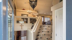 A staircase with a cross on the wall, a chandelier, and a door to the right. - CASA MIA - Las Vegas traditional Luxury (Las Vegas)