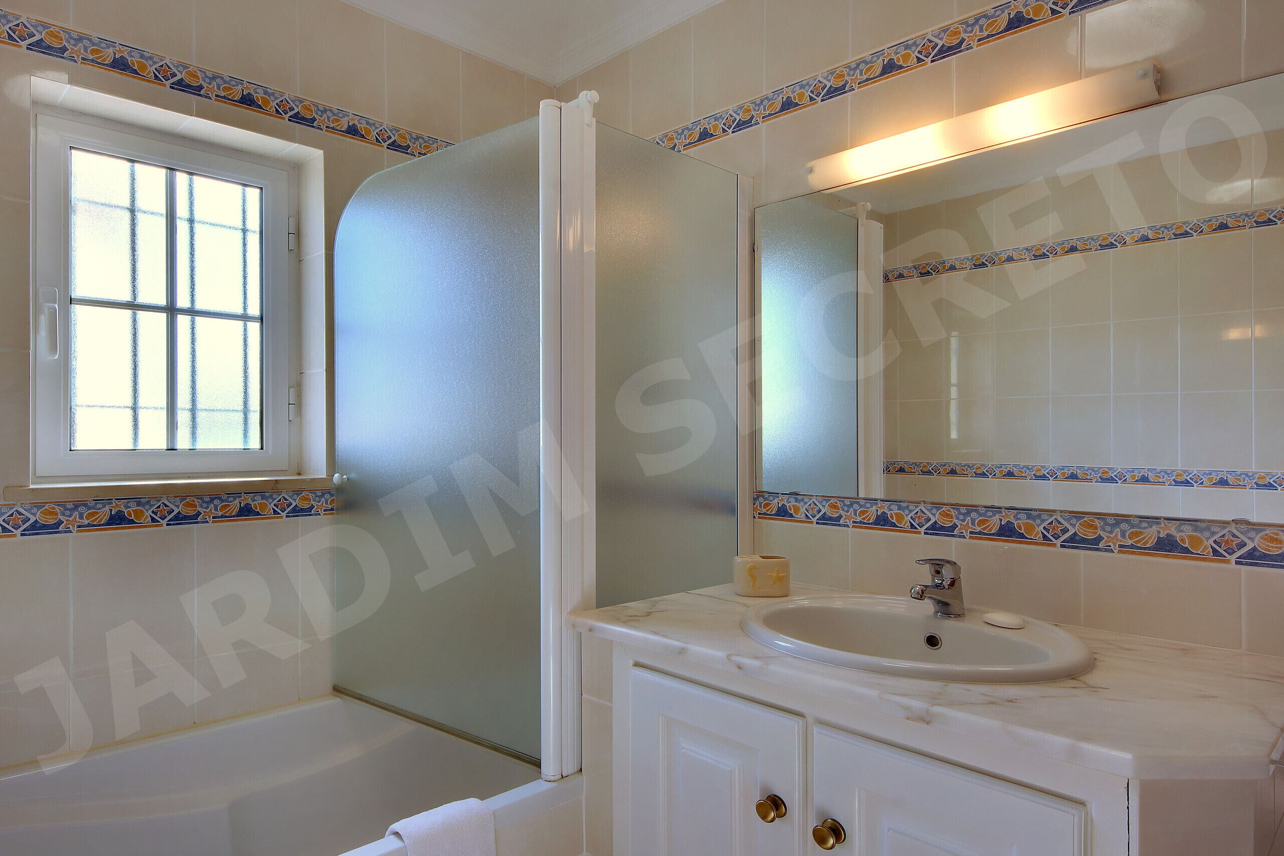 A bathroom with a window, a sink, and a mirror.