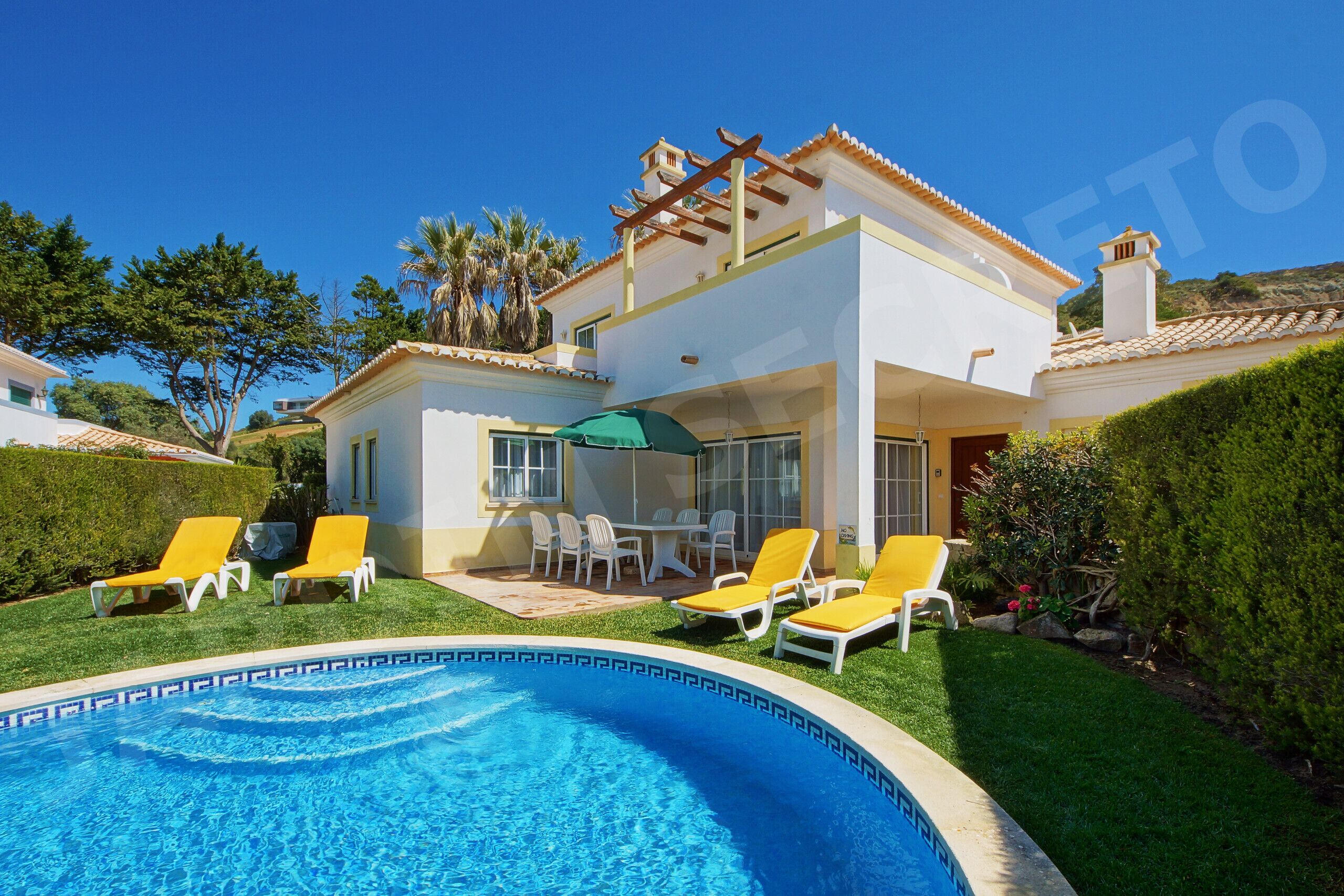 A two-story house with a swimming pool, outdoor seating, and a pergola.