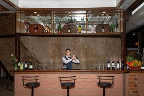 A bar area with a bartender, a brick wall, and various bottles and glasses.