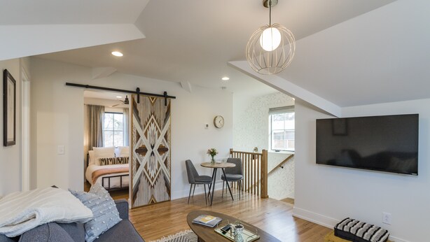 A modern living room with a sofa, coffee table, and a TV mounted on the wall. - The Russell House - Walk to Restaurants & Bars! (Nashville)
